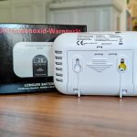 Rückseite eines Kohlenmonoxid-Warnmelders GS828 mit Verpackung auf Holztisch, zeigt Montagehalterung und technische Details