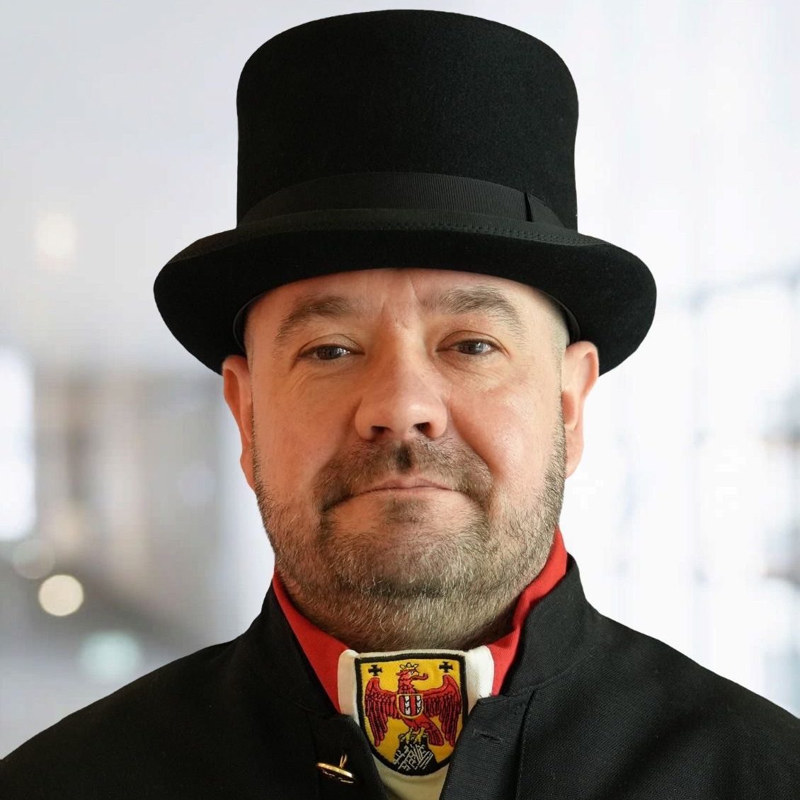 Porträt von Roland Grieer, Rauchfangkehrermeister im Burgenland, in traditioneller Handwerkskleidung mit Zylinder und Wappenkragen