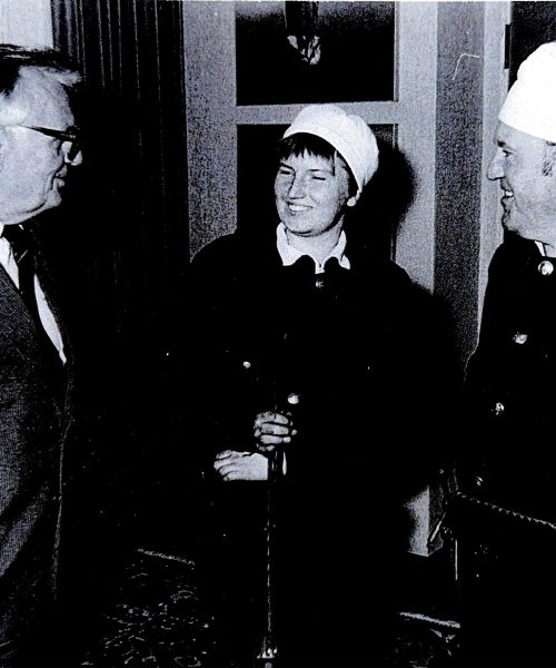 Schwarzweißfoto mit zwei Rauchfangkehrern in traditioneller Uniform im Gespräch mit einem Mann im Anzug, vermutlich bei einem offiziellen Anlass oder Besuch
