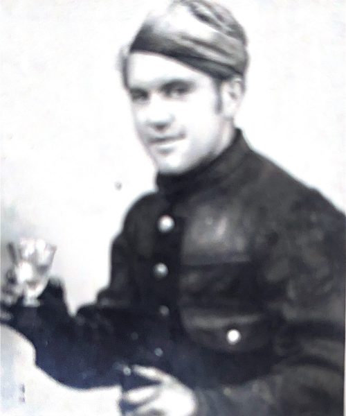 Altes Schwarz-Weiß-Foto eines jungen Rauchfangkehrers in Uniform und Haube, der ein Glas in der Hand hält – traditionelles Handwerksmotiv